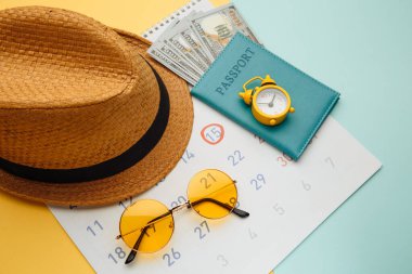 Tatil planlama konsepti. Seyahat hazırlığı: güneş gözlüğü, pasaport ve tatil planı sarı mavi arka planda takvimde yazılı