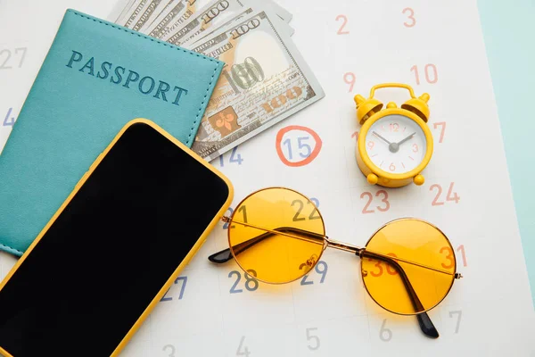 Viajes, turismo, concepto de vacaciones. Calendario con pasaporte, gafas de sol y primer plano de smartphone —  Fotos de Stock
