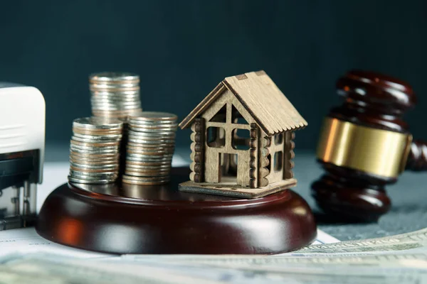 Una fila de monedas en un modelo de casa pequeña y un martillo de subasta de la ley — Foto de Stock