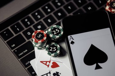 Çevrimiçi poker teması. Kumar çipleri, akıllı telefon ve yakın plan klavyede iskambil kartları