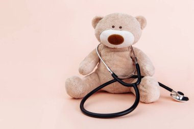 Oyuncak ayı, elinde fotokopi alanı olan bir steteskop tutan bir çocuk doktoru olarak sunuluyor.