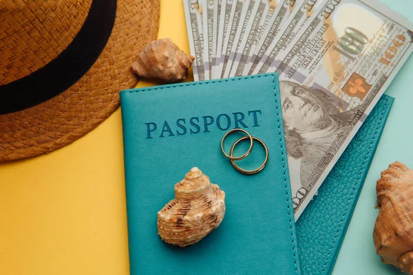 Ταξίδι μήνα του μέλιτος έννοια. Διαβατήρια με χρήματα, τουριστικό καπέλο και όστρακα από κοντά σε μπλε κίτρινο φόντο — Φωτογραφία Αρχείου