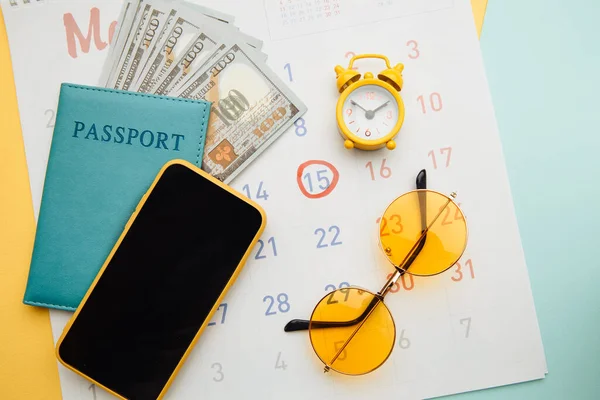 Calendario con pasaporte, gafas de sol y smartphone sobre fondo azul. Viajes, turismo, concepto de vacaciones —  Fotos de Stock