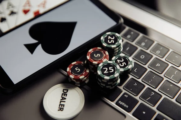 Tema online poker casino. Chip judi, smartphone dan bermain kartu pada keyboard laptop Stok Lukisan  