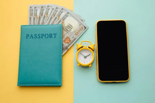 Conceito de viagem de verão. Relógio despertador, smartphone e passaporte com notas de dinheiro em fundo colorido — Fotografia de Stock