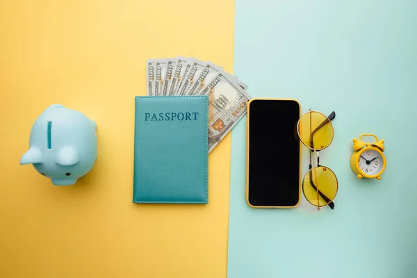 Ahorra para viajar. Planificación de viajes con alcancía, smartphone, gafas de sol y pasaporte con dinero sobre fondo colorido —  Fotos de Stock