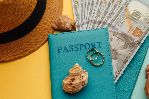 Planejando conceito de viagem de lua de mel. Passaportes com dinheiro, chapéu de turista e conchas close-up em um fundo azul amarelo — Fotografia de Stock