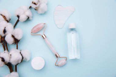 Mavi arka planda yüz masajı için Jade Roller. Ev konseptinde güzellik bakımı