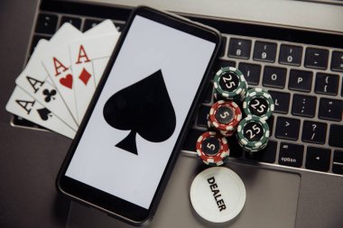 Çevrimiçi poker teması. Kumar çipleri, akıllı telefon ve klavyede iskambil kartları