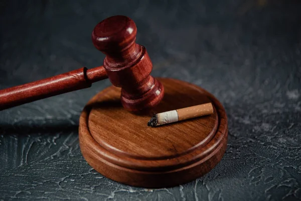 Wooden judge gavel near cigarette. Tobacco law