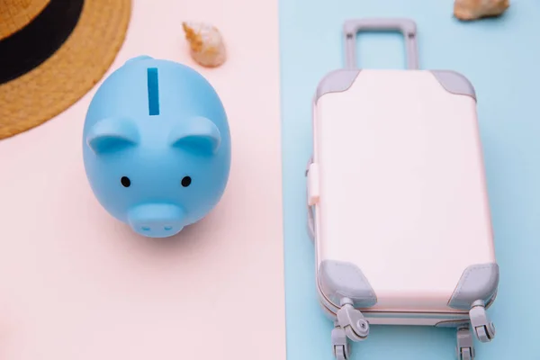 Concepto de turismo y viajes. Mini maleta de equipaje de viaje, sombrero y alcancía sobre fondo rosa azul de cerca —  Fotos de Stock