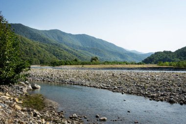 Dağların ve gökyüzünün arka planında bir dağ nehri. Psezuapse. Soçi.