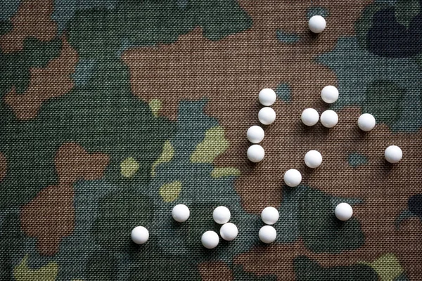 Hava yumuşaklığı topları kamuflaj kumaş üst görüşün arka planına saçılmıştır.