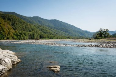 Dağların ve gökyüzünün arka planında bir dağ nehri. Psezuapse. Soçi.