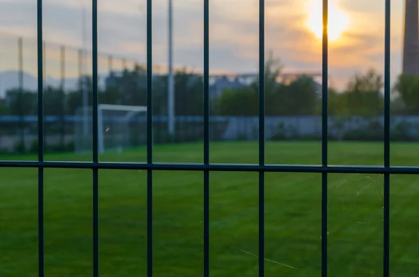 足球场上有绿色草坪日落 运动和团队比赛 越过栅栏 — 图库照片