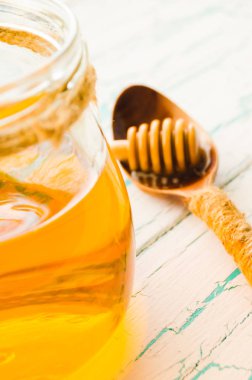 Bir kavanoz ve bir kaşık bal kırık boya ahşap arka plan ile eski bir tarih için taze bal. Parlak bir ışık ile.