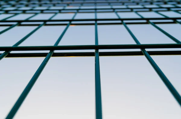 Metal mesh fence, fence on blue sky background.Rectangular abstraction close-up.