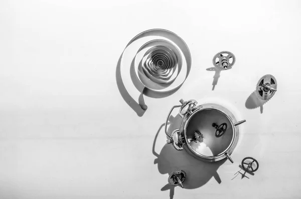 Disassembled alarm clock with scattered gears with a view from the top in black and white.