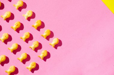 Sert gölgeler ile parlak ışık pembe bir arka plan üzerinde balık şeklinde kurabiyeler. Yakın çekim.