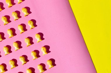 Pembe ve sarı zemin üzerine bir balık şeklinde kurabiyeler. Parlak gün ışığında gölgeler.