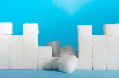 Mavi arka plan yakın çekim üzerinde rafine şeker küplerini duvar yıkıldı. Koruma ve dokunulmazlık.