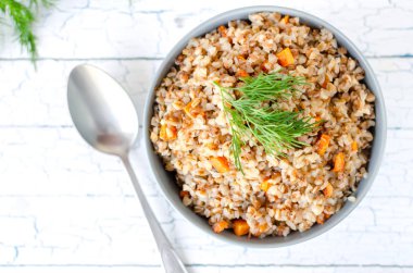 Buckwheat porridge with carrots and dill, top view on a light background. clipart