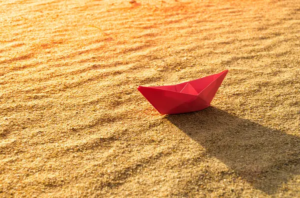 Barco de papel rojo en el fondo de un mar seco. Playa, calor y vacaciones.Ecología, sequía . —  Fotos de Stock