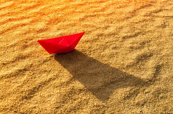 Rotes Papierboot auf dem Grund eines trockenen Meeres. Strand, Hitze und Urlaub. Ökologie, Dürre. — Stockfoto