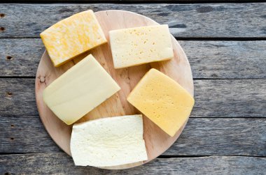 Eski, rustik ahşap bir masada çok çeşitli peynirler.