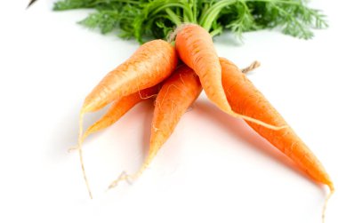 Beyaz arka planda yeşil yeşillikli taze havuç.