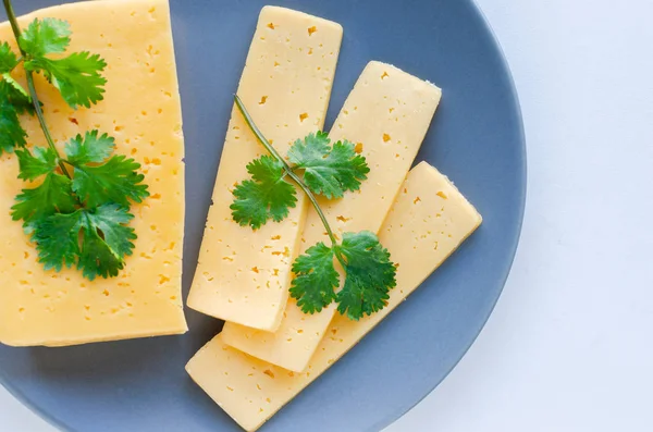 Dilimlenmiş maydanoz peyniri beyaz bir arka plan üzerinde gri bir tabak üzerine yayıldı.