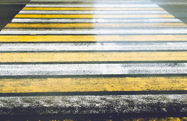 Скользкая дорога с пешеходным переходом окрашенная желтой и белой зеброй с бликами после дождя . — стоковое фото