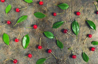 Olgun, üstten bir görünüm ile eski, rustik taş arka plan üzerinde yeşil yaprakları ile parlak kiraz.