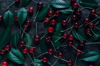 Olgun, üstten bir görünüm ile eski, rustik taş arka plan üzerinde yeşil yaprakları ile parlak kiraz.