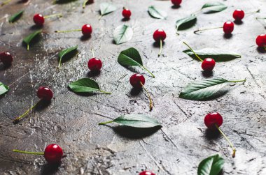 Güneşli bir şafak ile eski, rustik beton zemin üzerinde yaprakları ile Kiraz meyveleri.