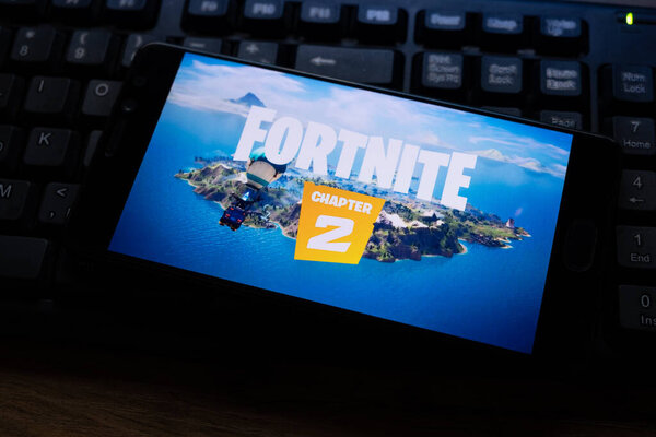 Костанай, Казахстан, 15 октября 2019.Мобильный телефон на фоне клавиатуры, с логотипом популярной игры fortnite 2, от Epic Games
.