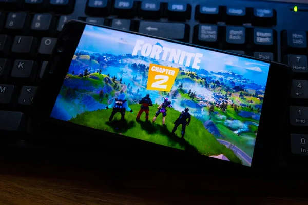 Kostanay, Kazajstán, 15 de octubre de 2019.Teléfono móvil en el fondo del teclado, con el logotipo del popular juego fortnite 2, de Epic Games . —  Fotos de Stock