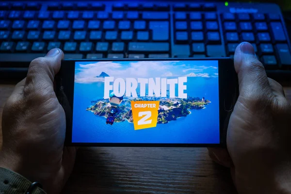 Kostanay, Kazajstán, 15 de octubre de 2019.Un hombre sostiene un teléfono móvil con un salvapantallas del popular juego Fortnite 2, de Epic Games . — Foto de Stock