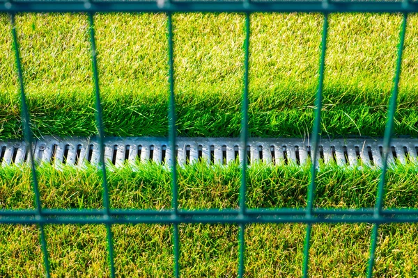 Sistema de drenagem no campo de futebol com um gramado verde brilhante . — Fotografia de Stock