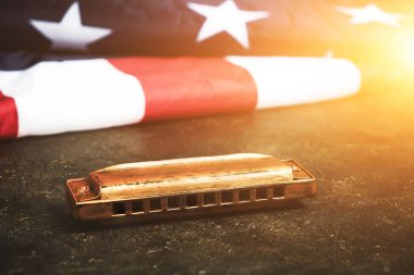 Amerika Birleşik Devletleri bayrağının arka planında mızıka. Müzik aleti. Güneş ışığında yıldızlar ve çizgiler.