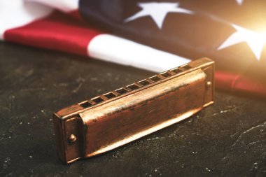 Amerika Birleşik Devletleri bayrağının arka planında mızıka. Müzik aleti. Güneş ışığında yıldızlar ve çizgiler.