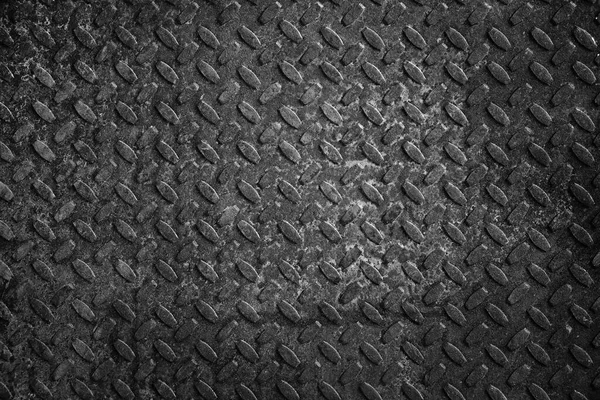 Old and rusty metal floor in black and white. Texture of a rough metal sheet with a convex pattern