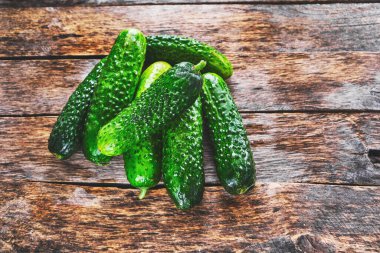 Eski ahşap bir masada taze sulu yeşil salatalıklar.