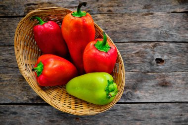 Köy ahşap bir masada hasır sepetteki dolmalık biberler.