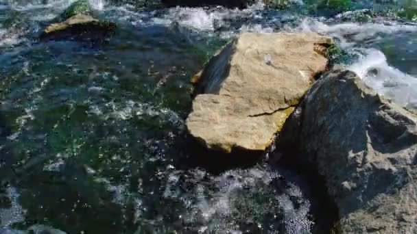 Spěchající, rychlý proud vody mezi kameny v horské řece.