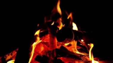 Ölen bir adam ateşe odun atar. Alevlere yakın çekim..