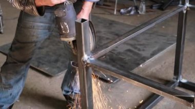 Kaynakçı kaynak makinesiyle dikişleri işliyor, kıvılcımlar uçuşuyor.