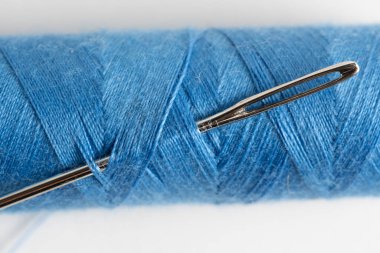 Beyaz arka planda iplik ve iğne dikmek. Kapat.