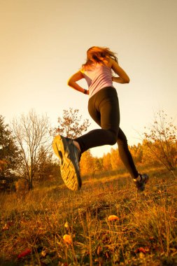 Koşma ve atlama park doğal ortamda gün batımında kız
