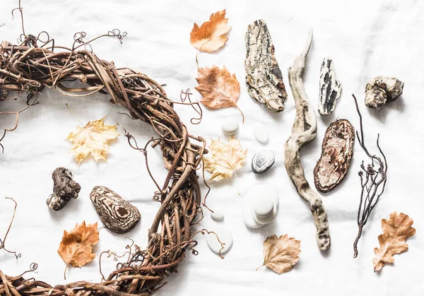 Natural nature objects for creative crafts - vine wreath, stones, leaves, wood on a light background, top view. Homemade creativity concept